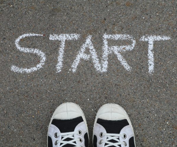 Close-up of sneakers and a 'START' chalk drawing on pavement, symbolizing new beginnings.