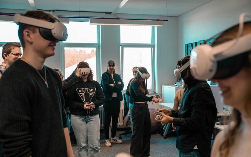 A group of diverse adults using VR headsets in an office setting.