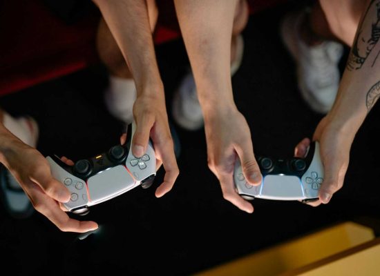 Two gamers playing with wireless controllers during a gaming session indoors.
